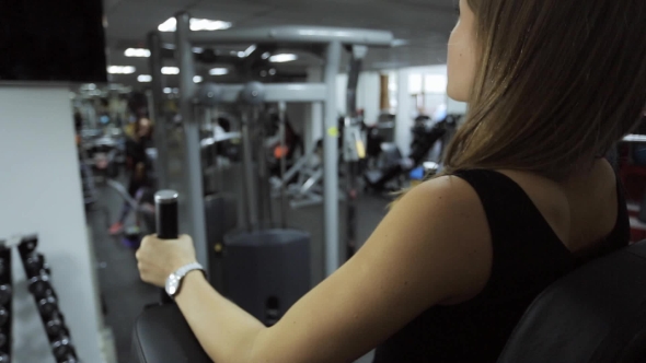 Woman Performs an Exercise on Rise of Leg Raises in Gym on Simulator. alt