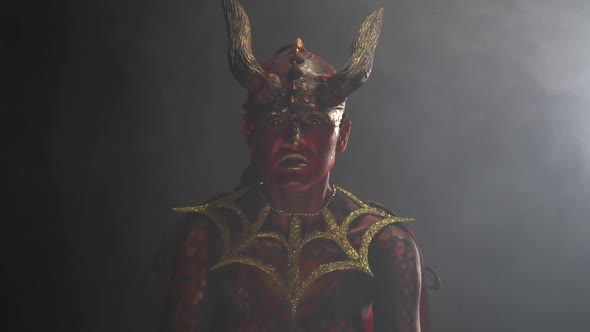 Golden armor on an evil demon with massive horns and red eyes, in the smoke alt