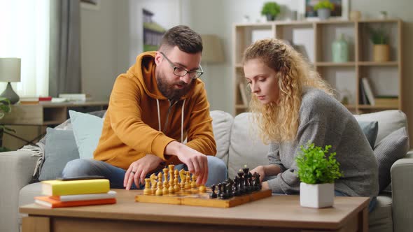 Happy Young Adult Couple Learning to Play Chess alt