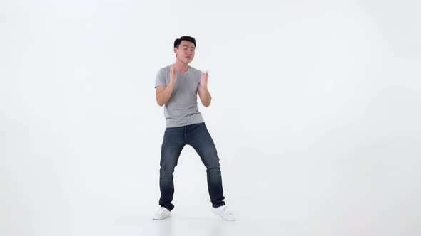 Full body of happy young Asian man dancing on white background