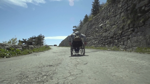 Disabled Man Pushes Himself Up The Road