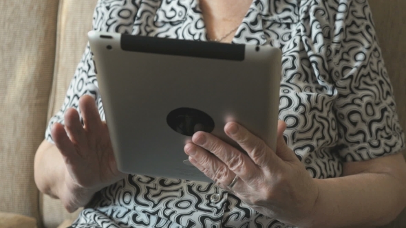 An Old Woman Viewing Photos Using a Digital Tablet alt