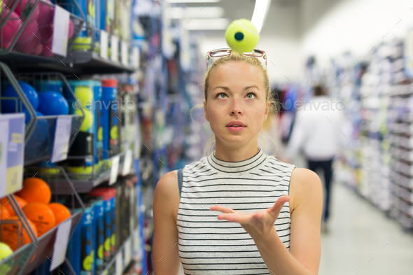 Woman shopping tennis balls in sportswear store.