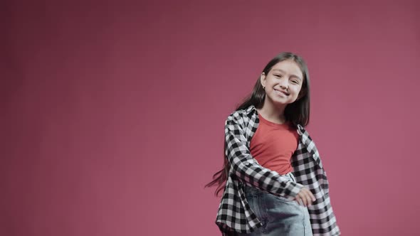 Little Girl is Happy Dancing and Spinning Smiling on a Pink Background