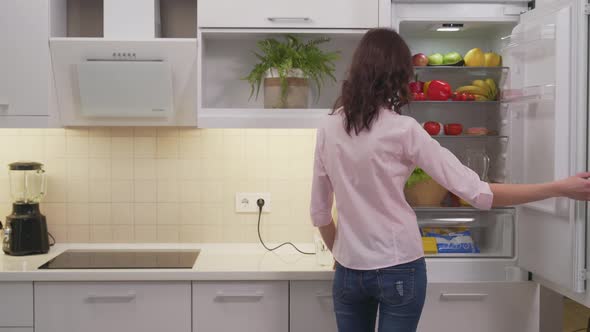 Attractive Woman Taking Pitcher with Juice From Refrigerator alt