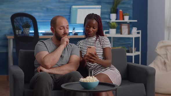Interracial Couple Looking at Smartphone Screen at Home alt