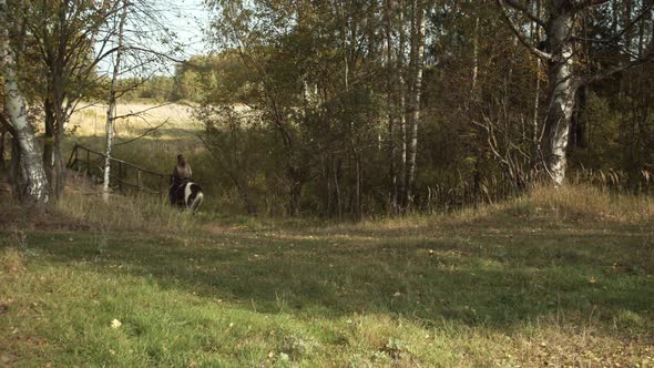 A Young Country Girl Walks on a Horse Through the Village on an Autumn Day. Rural Landscape, Forest alt
