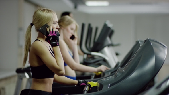 Woman Walking On Treadmill Talking On The Phone alt