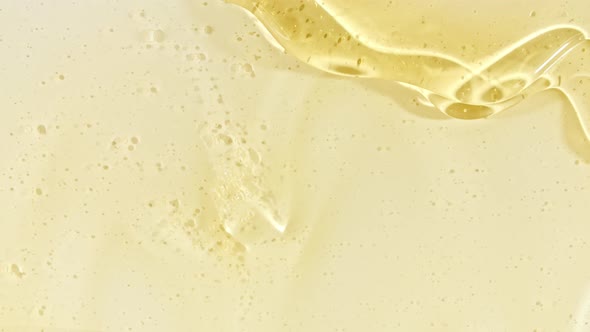 Yellow Transparent Cosmetic Gel Fluid With Molecule Bubbles Flowing On The Plain White Surface alt
