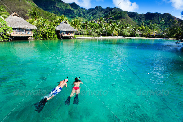 Young couple snorkeling in clean water over coral
