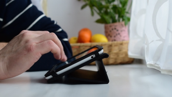 Young Male Uses Tablet On Window Sill