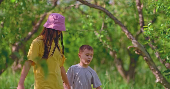 Friendly Sister and Younger Brother are Walking in the Park and Talking a Fun Walk Together alt
