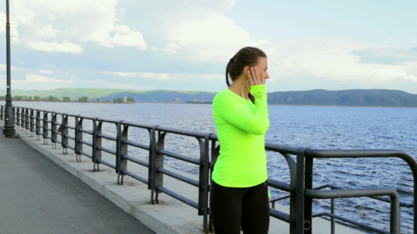 Brunette Woman In Sports Cloth Listening To Music At Embankment Take a Break alt