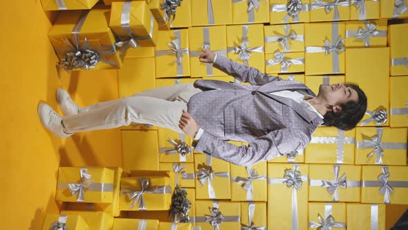 A Caucasian Man is Dancing Emotionally Among a Lot of Yellow Gift Boxes