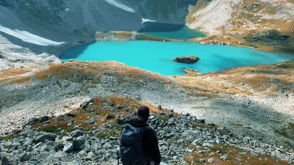 Traveler on the background of a huge lake in the mountains with blue water alt