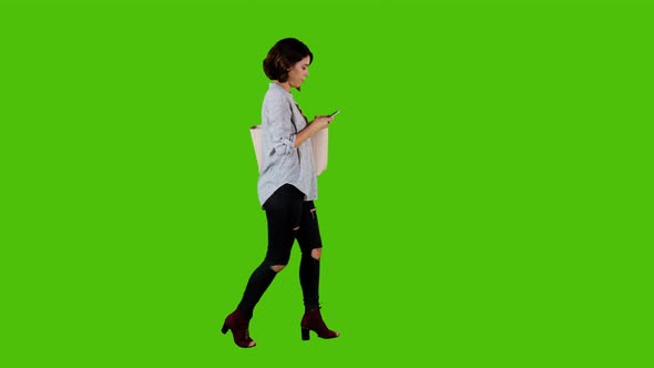 Using an app happily while walking by a casual woman over green screen. 4K alt