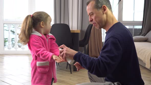 Hand Hygiene. Father treats child hands with disinfectant antiseptic spray. Covid-19 alt