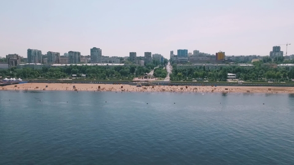 Camera Is Flying From River Through Beach To City Park