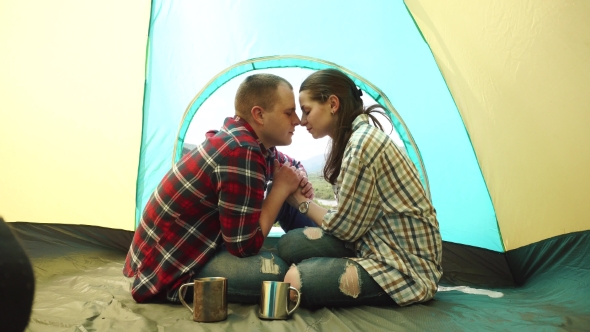 Young Tourist Couple Have a Sensual Moment In Tent At Windy Weather. Beautiful Young Man And Woman