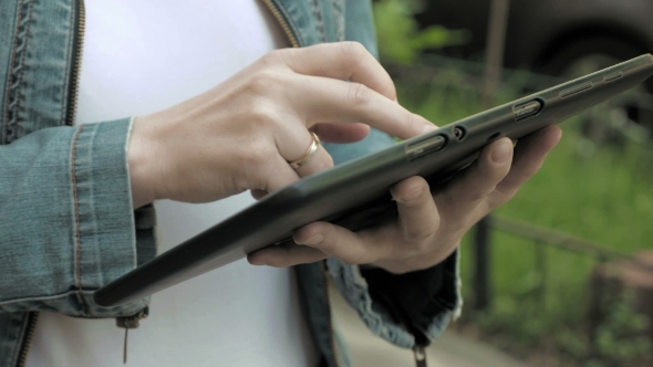 Woman Types Texts On Tablet Pc Walking Outdoors