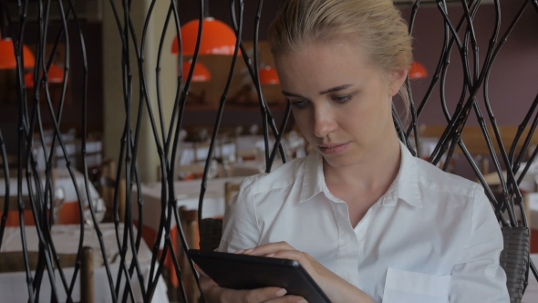 Young Beautiful Blonde Straight Hair Woman in the City Sitting at the Restaurant Using Tablet alt
