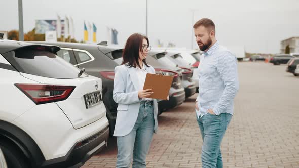 Male Customer Having Conversation with Competent Saleswoman While Choosing Car alt