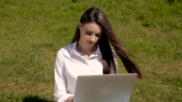 Portrait Of Cute Student Girl Working With Laptop In Park Of a University Campus alt