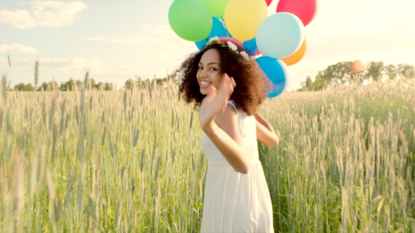 Young Girl Running Through a Wheat Field With Colour Balloons During Sunset alt