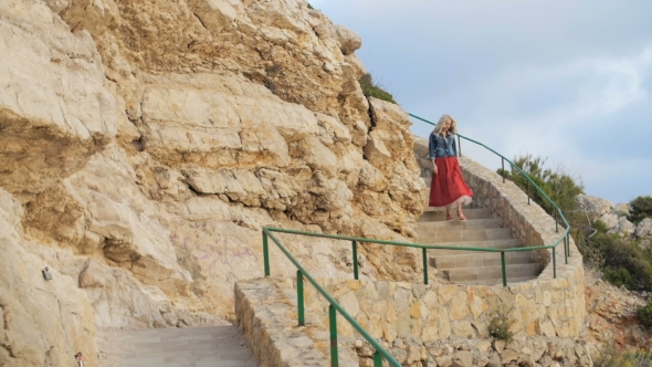 Romantic Girl In Red Skirt Walk Down The Stairs At The Coast Side