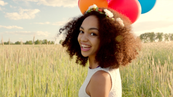 Young Girl Running Through a Wheat Field With Colour Balloons During Sunset alt
