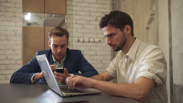 Two Businessmen Read News And Chatting In Social Networking Service On Modern Gadget. alt