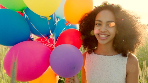 Young Girl Running Through a Wheat Field With Colour Balloons During Sunset alt