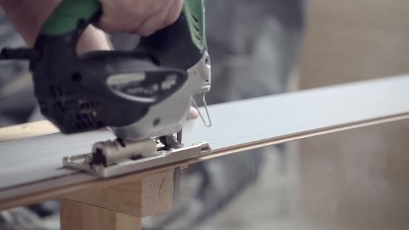 Man Sawing Laminate with Jigsaw at Construction Site alt