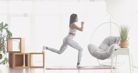 Young black woman making lunges training at home.
