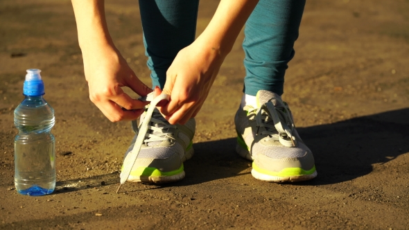 Girl Stopped Running To Tie The Laces On Running Shoes. Fitness Girl Training Outdoors.  alt