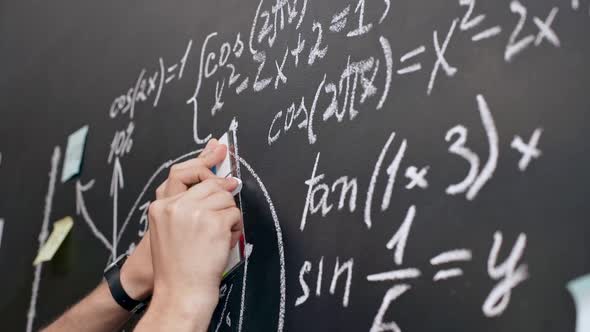 Close Up Teacher Man Hand Writing Math Formulas on Chalkboard with White Chalk