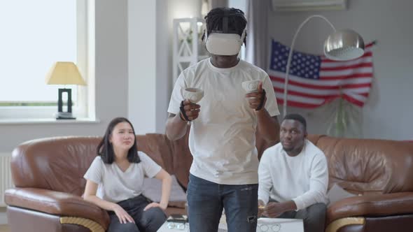 Smiling Confident Man in VR Headset Boxing Shadow in Augmented Reality with Friends Cheering at alt