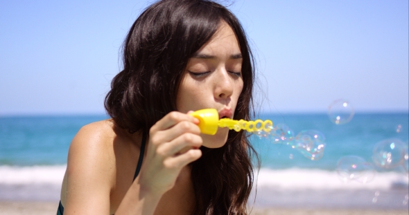 Young Woman Blowing Soapy Iridescent Bubbles alt