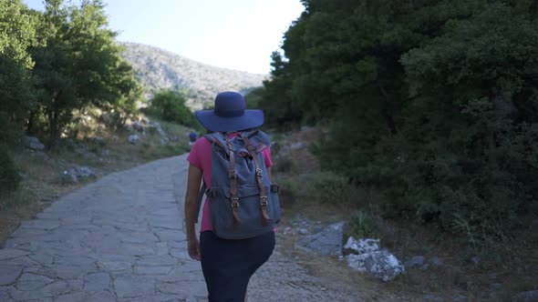The Camera Follows a Woman with a Backpack Walking in the Old City of Greece