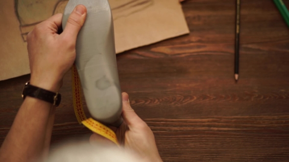 Shoe Fashion Designer Taking Measurements On Feet Mannequin In His Studio
