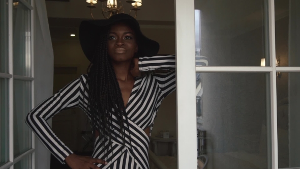 Elegant Attractive Black Lady In Black Hat And Striped Cocktail Dress Posing At Her Luxury