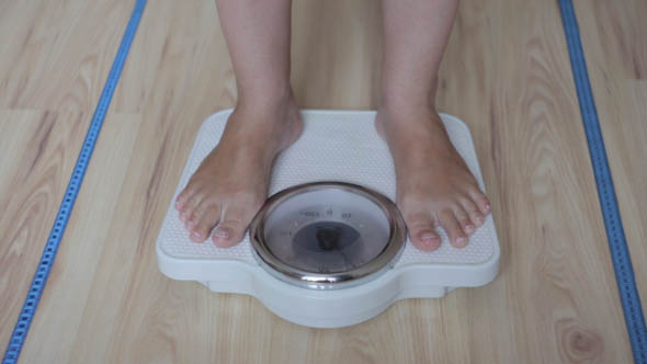 The Girl Checks for the Weight on the Scales of alt