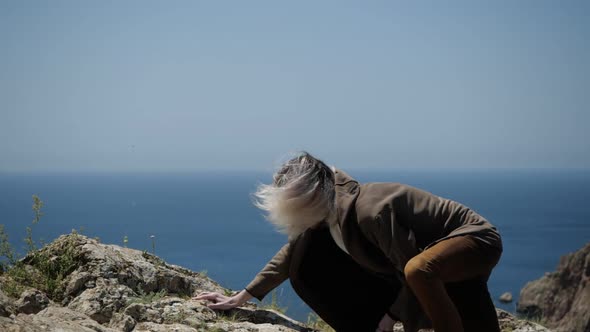 Reaching the Top of a Mountain in Crimea Is a Young Man with Long Hair 