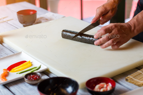 Hand with knife cuts sushi