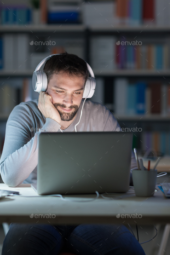 Smiling man networking late at night - Stock Photo - Images