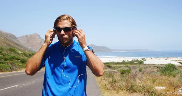 Triathlete man wearing earbuds in the countryside road alt