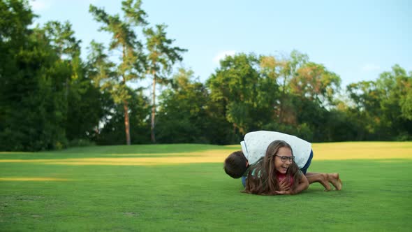 Brother and Sister Playing Together in Field. Father Looking at Kids in Meadow. alt