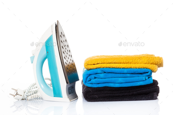 Electric iron and pile of clothes. electric iron isolated on whi