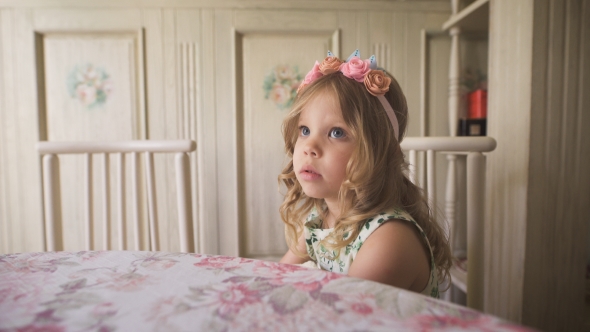 Thoughtful Little Girl Looking Away While Sitting At The Table In a Bright alt