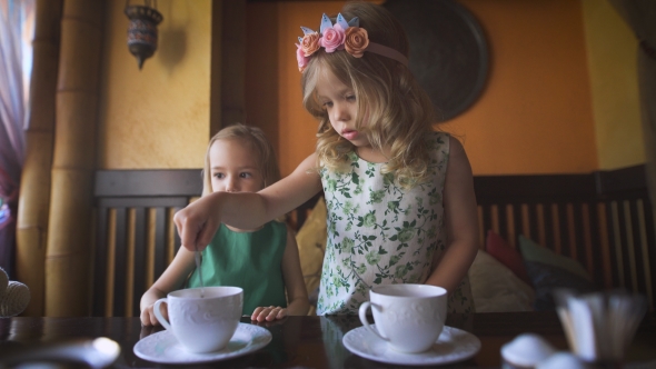 Two Pretty Little Girls Are Having Tea In a Cafe alt